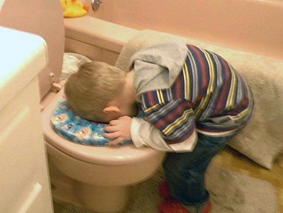 Boy sticking head in toilet